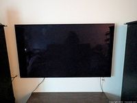 Wall-mounted 65-inch flat screen TV with cords visible