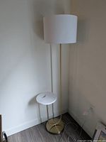 Full view of gold floor lamp with side table and shade