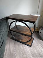 Full view of side table beside sofa showing top, shelves and metal frame