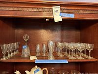 Shelf with assorted pressed glass stems and bell