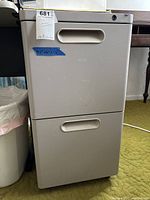 Front view of beige 2-drawer filing cabinet showing recessed handles and lock