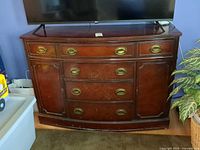 Front view of dresser showing brass hardware, curved front, overall wear
