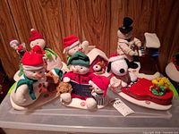 Group view of seven Hallmark animated Christmas plush decorations on bin lid