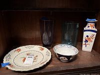 Overall view of charger, bowl, vase and two tumblers on shelf