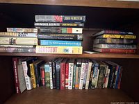 Shelf with stacked hardcovers and row of paperbacks including titles by John Feinstein, Jack McCallum, Dick Francis, etc.