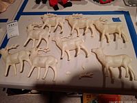 Group of nine white plastic deer figurines on tabletop