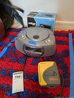 Group shot of Memorex CD clock radio, Sony Walkman Sports cassette player, and boxed Realtone radio