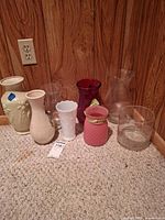Group of assorted vases on carpet against panel wall