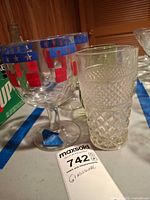 Group showing goblet with red/blue pattern beside clear pressed tumbler