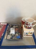 Overview of comics stack, two cartoon mugs and box