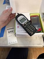 Motorola Talkabout resting on open box with Samsung red slider phone inside the box