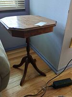 Full view of solid wood octagonal pedestal side table beside couch