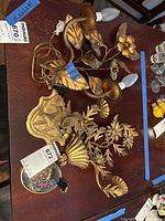 Pair of gilt floral sconces with bulbs and oval dried flower art on table