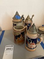 Four stoneware beer steins showing overall style and lids