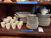 Overall view of stacked plates, cups, bowls and serving pieces in cabinet