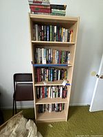 Full front view of tall light maple laminate bookcase with books showing scale