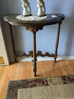Front view of dark brown solid wood demilune console table against wall