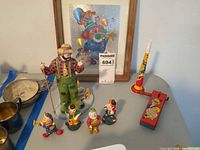Group shot of all clown figurines, two noisemakers and framed print