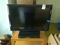 Front view of Vizio E320VL TV on stand with slim DVD player underneath