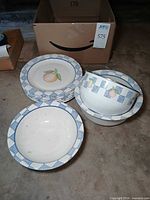 Stack of six fruit plates and enamel bowl showing Hopscotch pattern