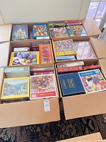Two XL boxes filled with stacked puzzle boxes, various brands and themes visible