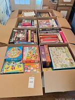 Eight open XL U-Haul boxes filled with assorted boxed jigsaw puzzles