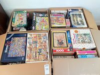 Open U-Haul boxes filled with numerous jigsaw puzzle boxes