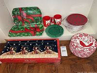 Overview of tableware on shelf showing trays, mugs, green plate, red plates stack, boxed Santa tray, red bird plates stack