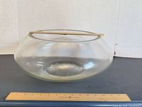 Clear glass punch bowl with ruler for scale, ladle resting across opening