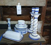 All items grouped: two tall spiral candlesticks, one short candlestick, stacked bowls and cups, butter dish with lid
