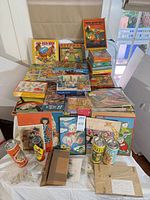 Full table view showing stacked boxed puzzles, cylindrical puzzles, frame tray puzzles and inventory sheets