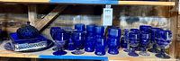 Shelf view showing goblets, relish tray in metal caddy, platter, candy dish