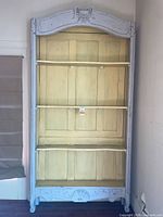 Front view of tall distressed French country bookcase with shelves