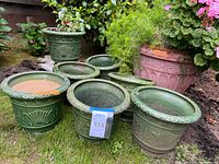 Group view showing seven green glazed planters and one pink terracotta planter