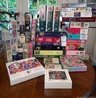 Overall view of approximately 28 puzzle boxes stacked on table