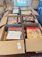 Eight XL U-Haul boxes filled with assorted jigsaw puzzles