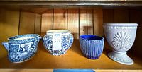 Shelf with four assorted ceramic planters in varying shapes and colors