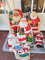 Group shot of all six molded plastic Santa decorations showing size reference