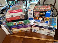 Both stacks of boxed puzzles on table showing brands and piece counts