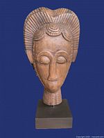 Front view of carved wooden head sculpture on base