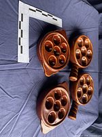 Four brown glazed escargot dishes with different handle styles