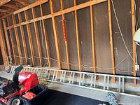 Full view of aluminum extension ladder lying along garage wall