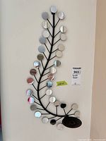 Full view of black metal wall sconce with mirrored discs and candle plate