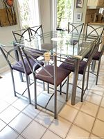 Complete dining set view highlighting four chairs around glass table
