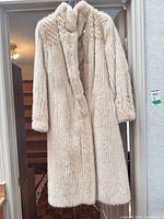 Full view of cream beige fur coat hanging