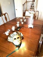 Mask, tealight branch holder and hurricane shown on dining table for scale