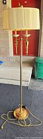 Full view of brass plated floor lamp with shade and base