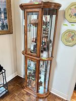 Full view of entire curio cabinet showing wood frame, glass panels, curved front