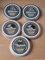 Front view of all five cologne tins showing labels
