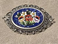 Front view showing micro-mosaic floral design and filigree frame